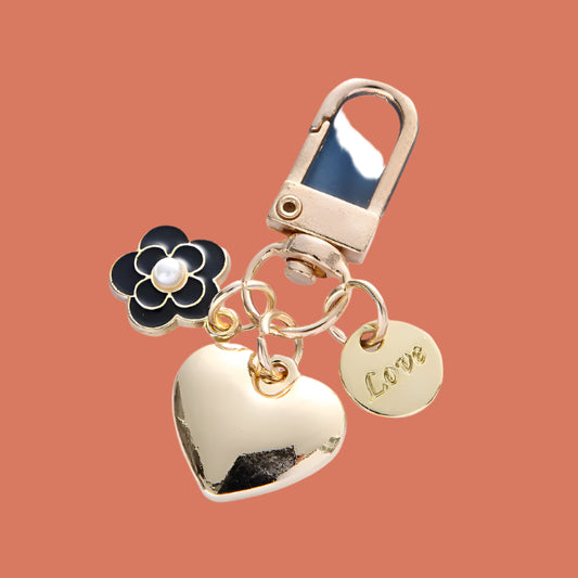 Gold keychain with heart charm, black flower charm, and 'LOVE' tag