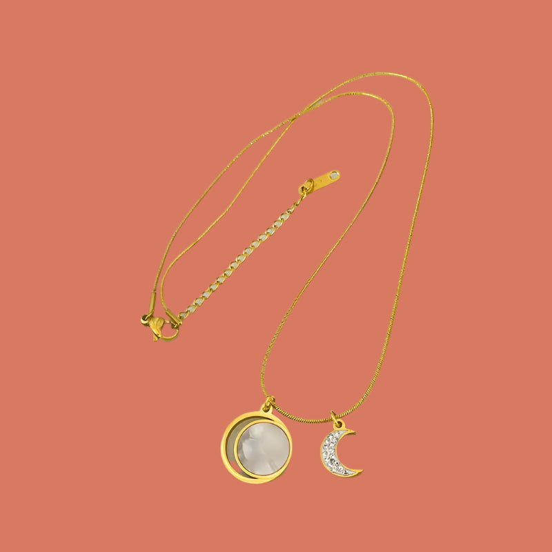 Gold necklace with moon and heart pendants.