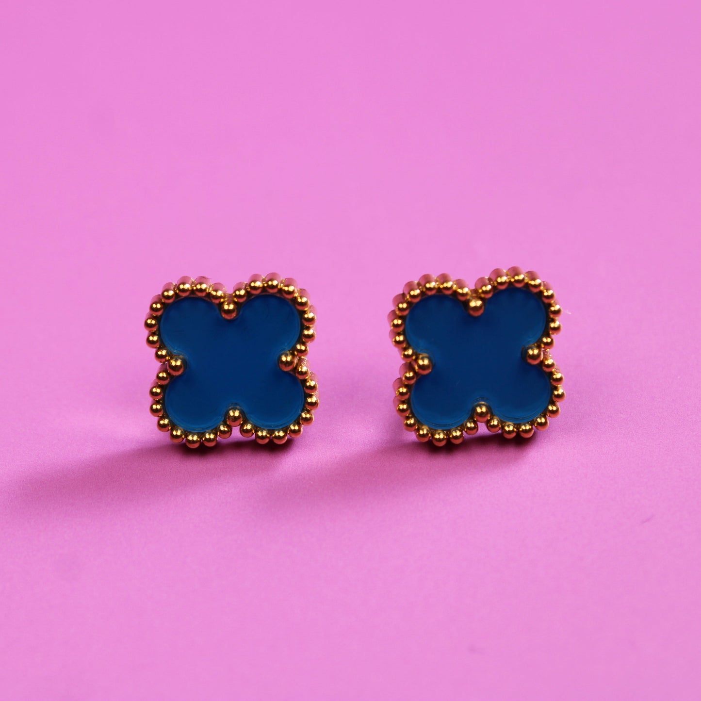 Blue butterfly-shaped earrings on a pink background