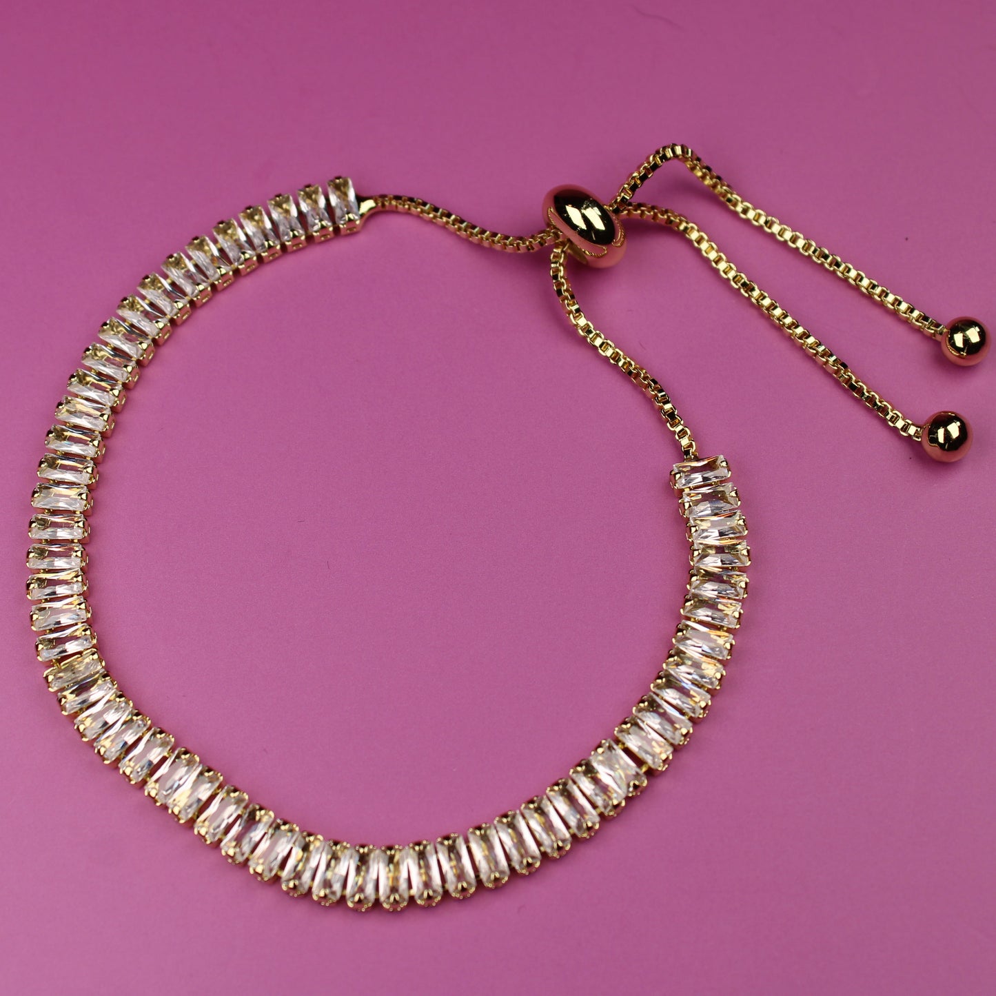 Gold beaded bracelet on a pink background