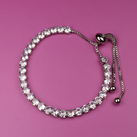 Silver bracelet with clear stones on a pink background