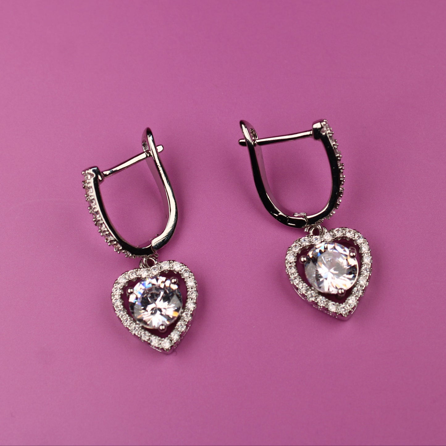 Heart-shaped earrings on a pink background