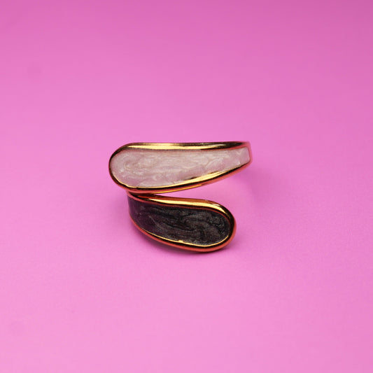 Two gold and black earrings on a pink background