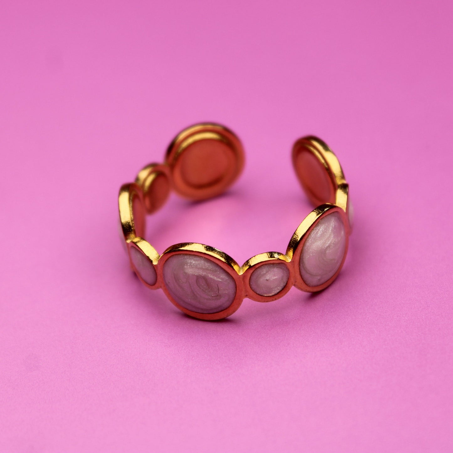 Gold ring with pink stones on a pink background