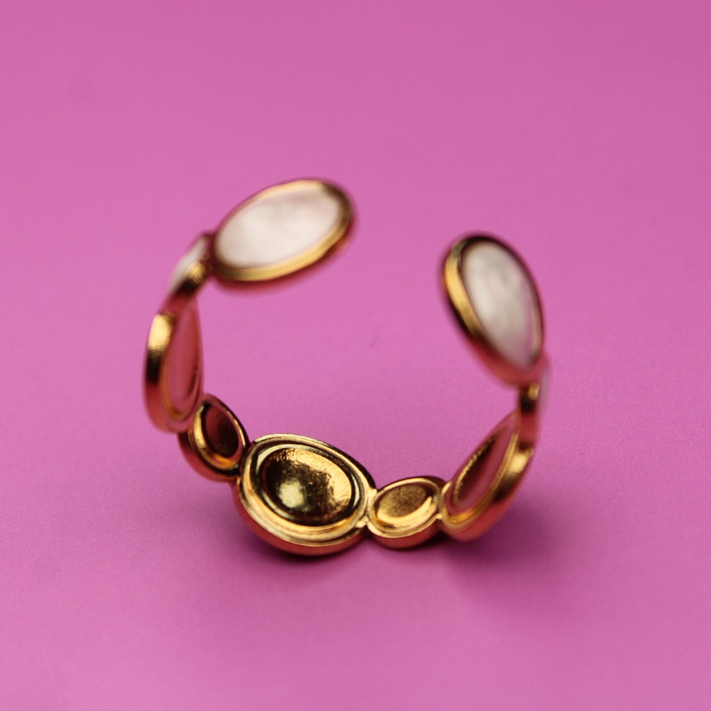 Gold ring with red stones on a pink background