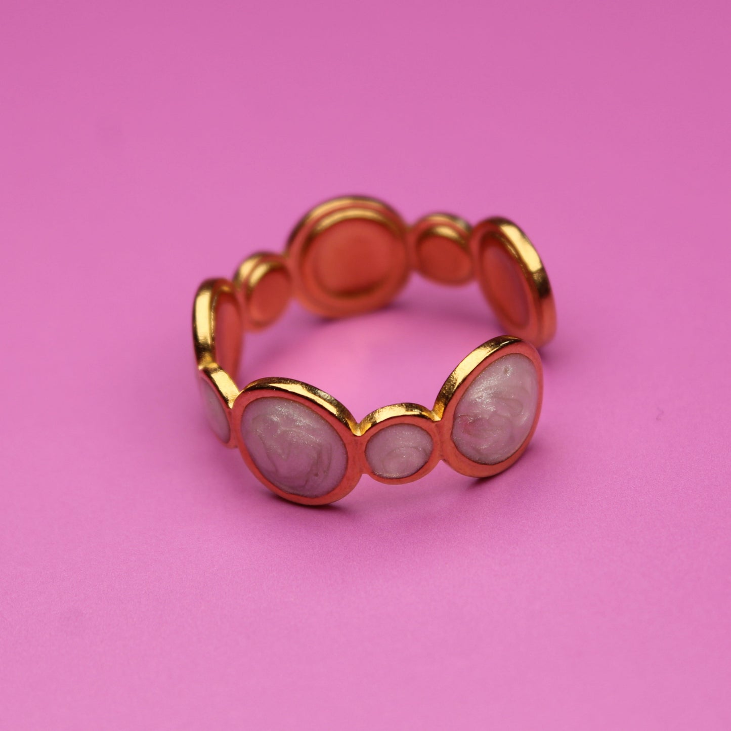 Gold ring with circular design on a pink background