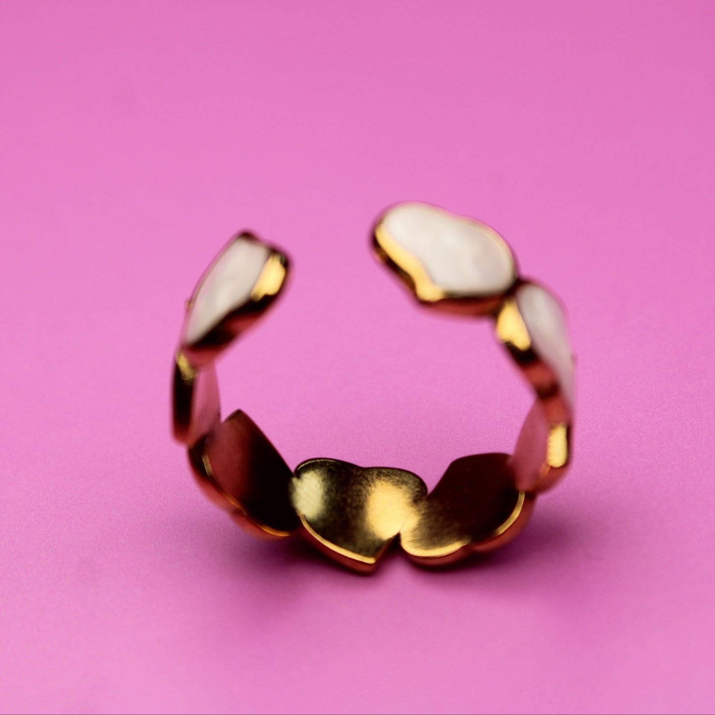 Gold ring with white stones on a pink background