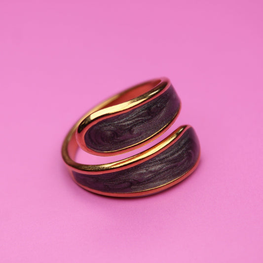 Gold and black ring on a pink background