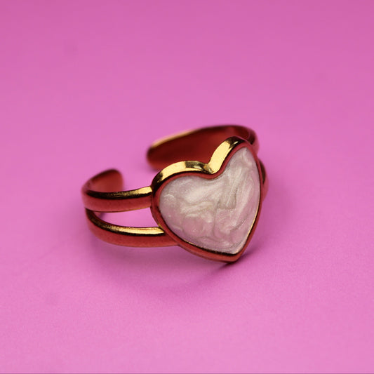 Heart-shaped ring with gold border on a pink background