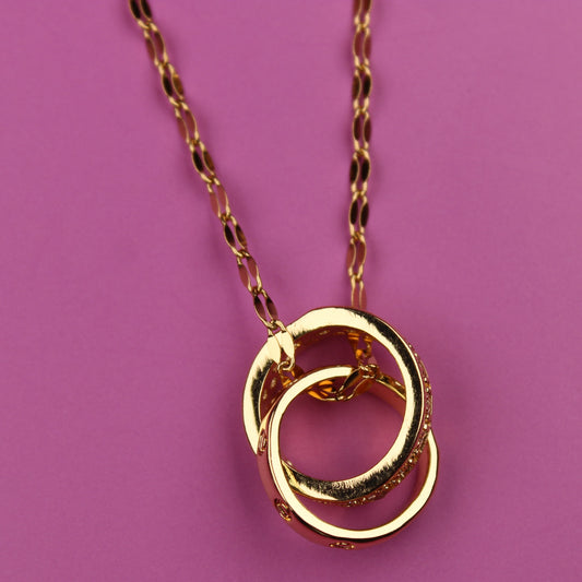 Gold necklace with interlocking rings on a pink background