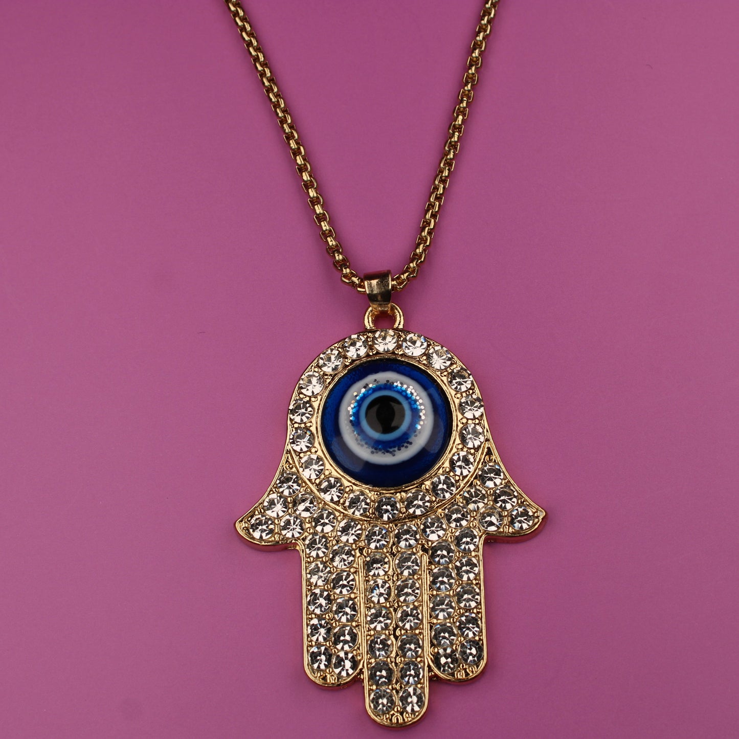 Hamsa hand necklace with a blue eye pendant on a pink background