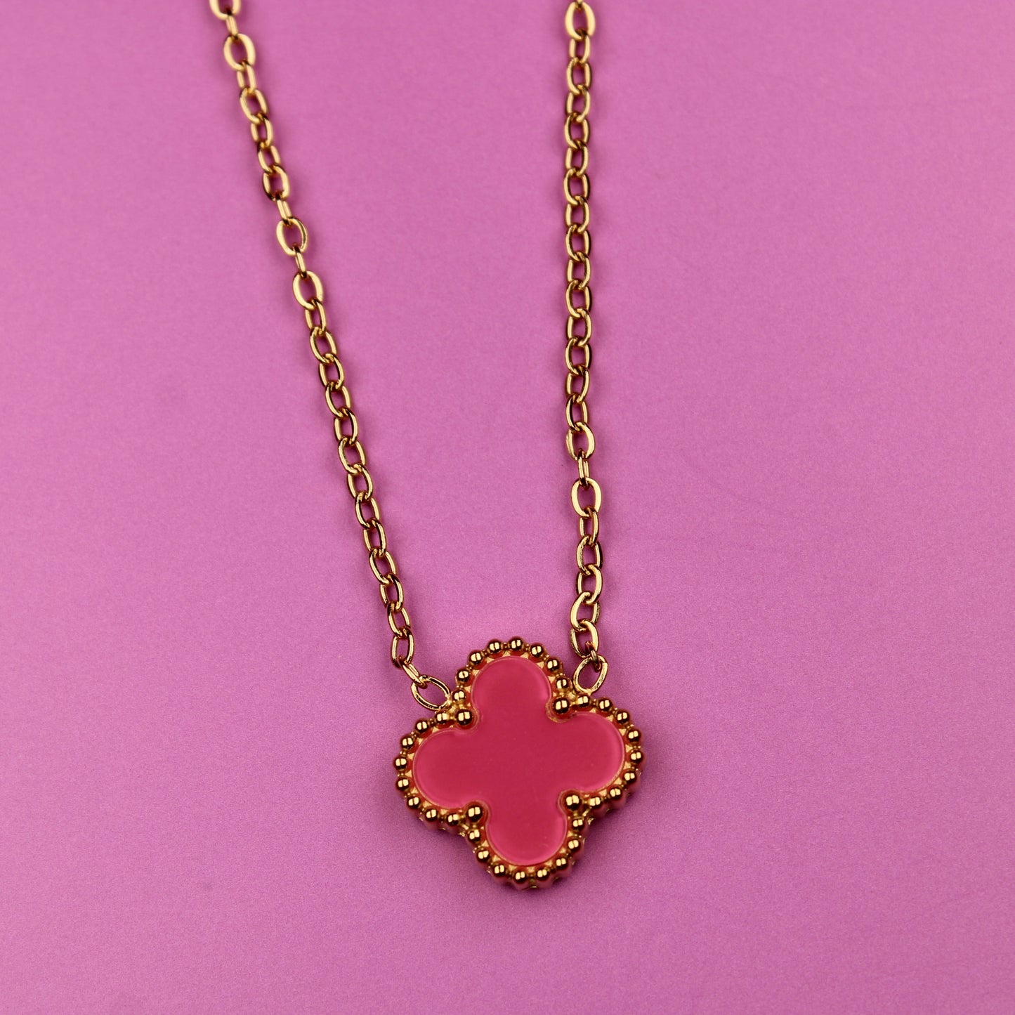 Necklace with a pink clover-shaped pendant on a pink background