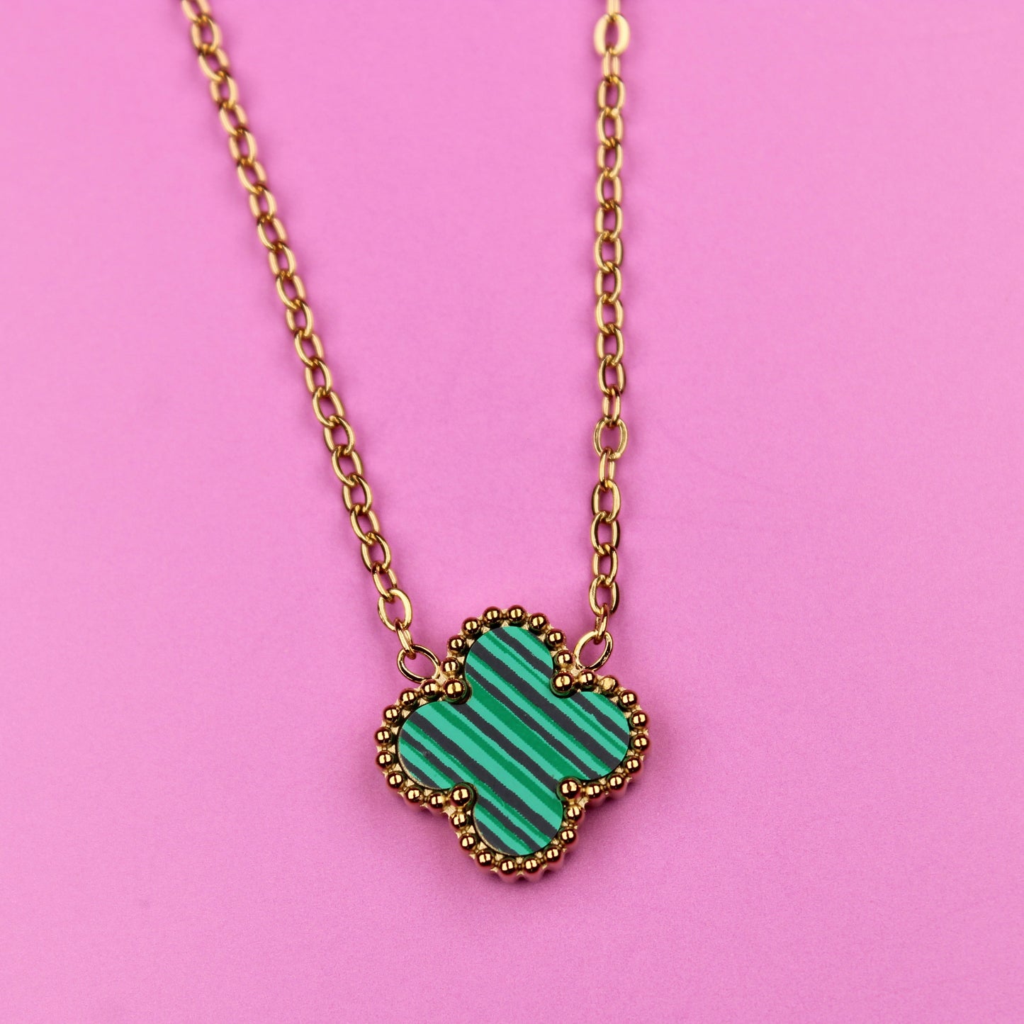 Necklace with a green heart-shaped pendant on a pink background