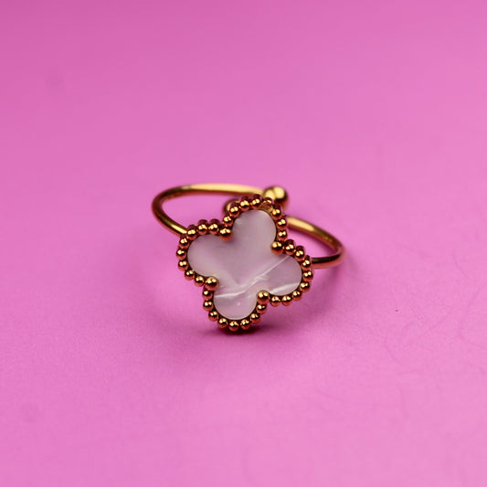 Gold ring with a white stone on a pink background