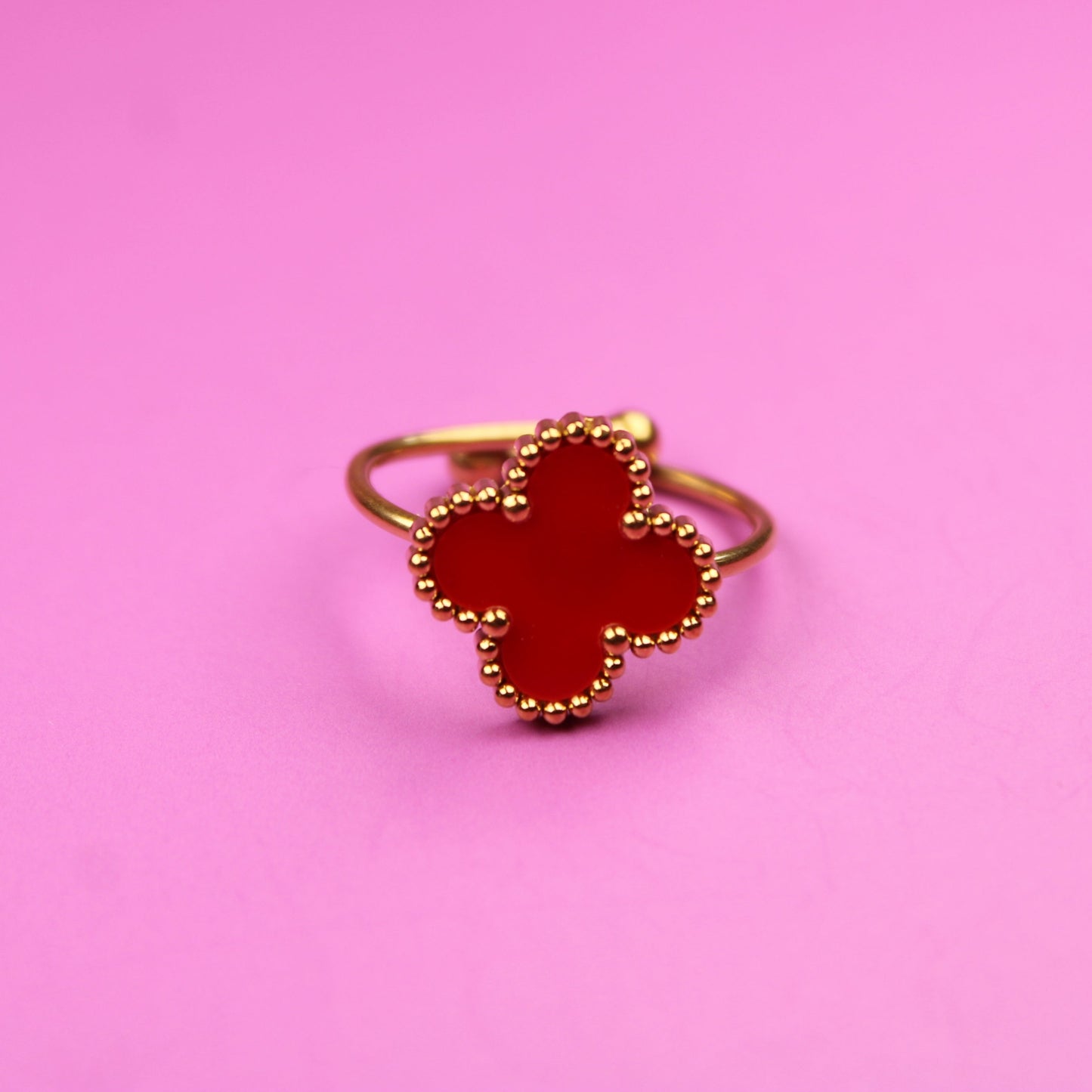 Gold ring with red gemstone on a pink background