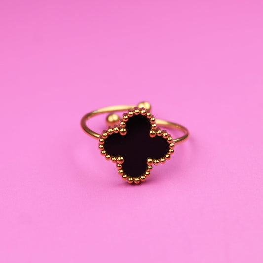 Gold ring with a black gemstone on a pink background