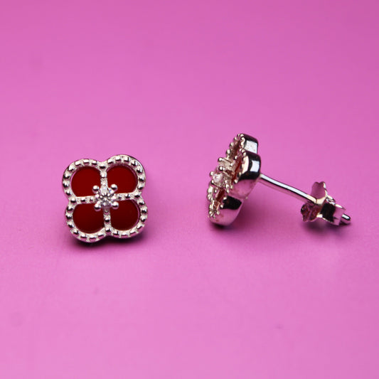 Pair of earrings with red gemstones on a pink background