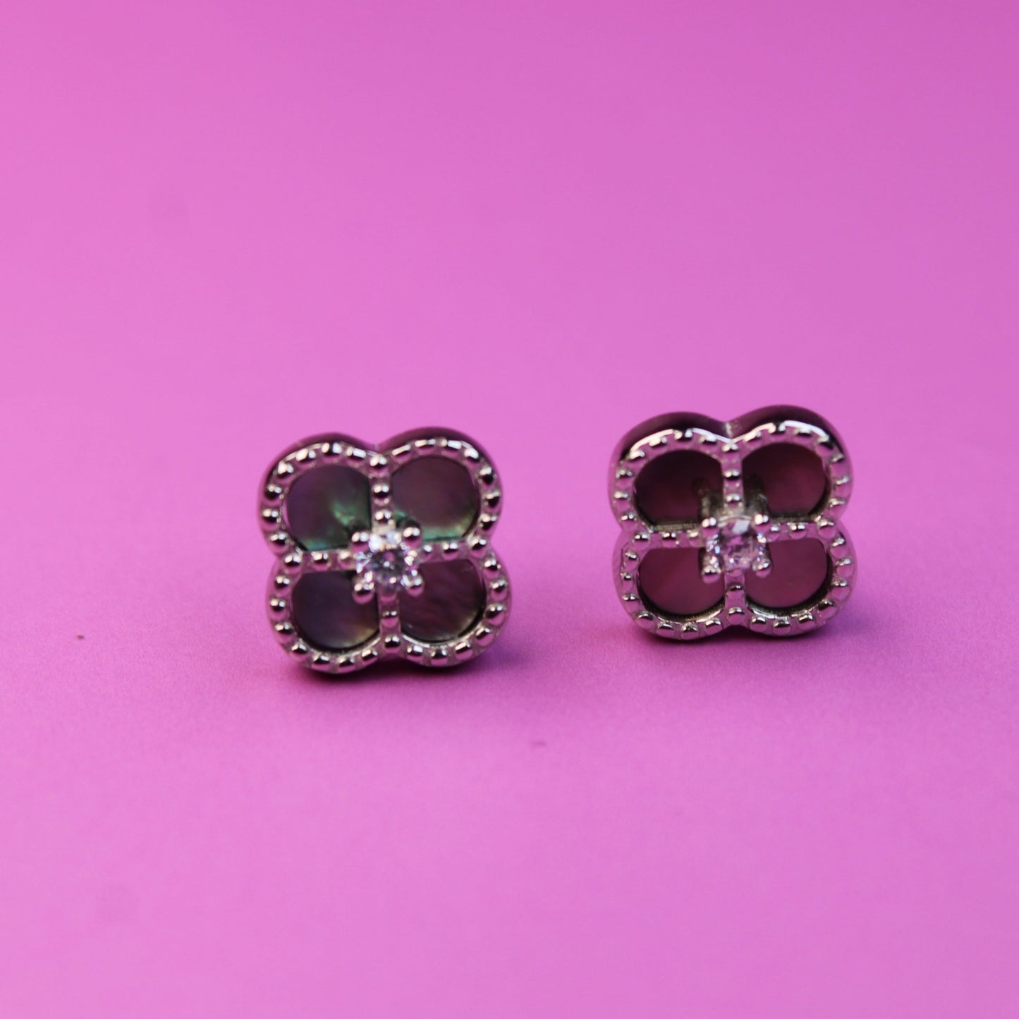 Pair of earrings with red gemstones on a pink background
