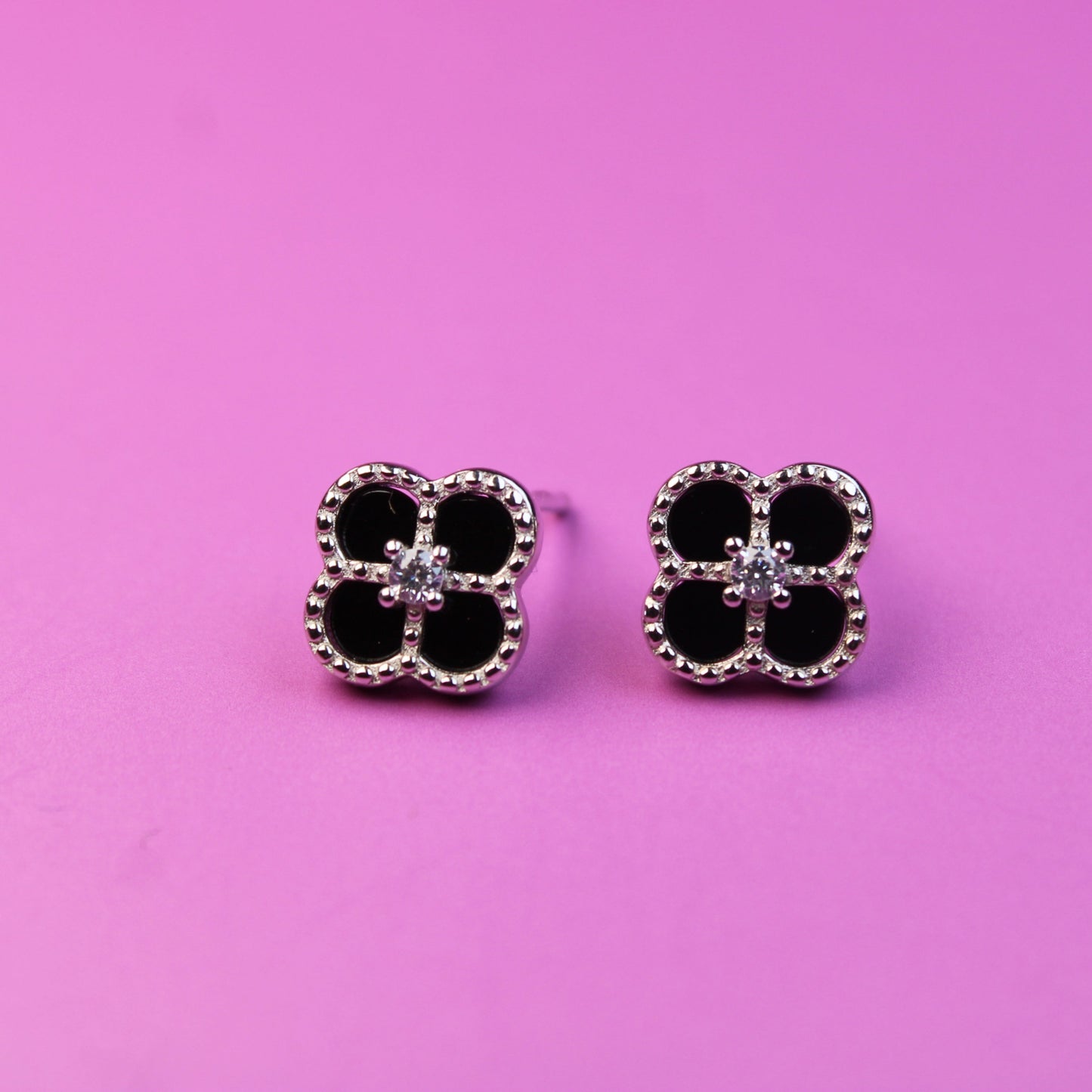 Pair of black and silver earrings on a pink background