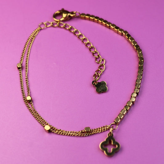 Gold chain bracelet with charms on a pink background