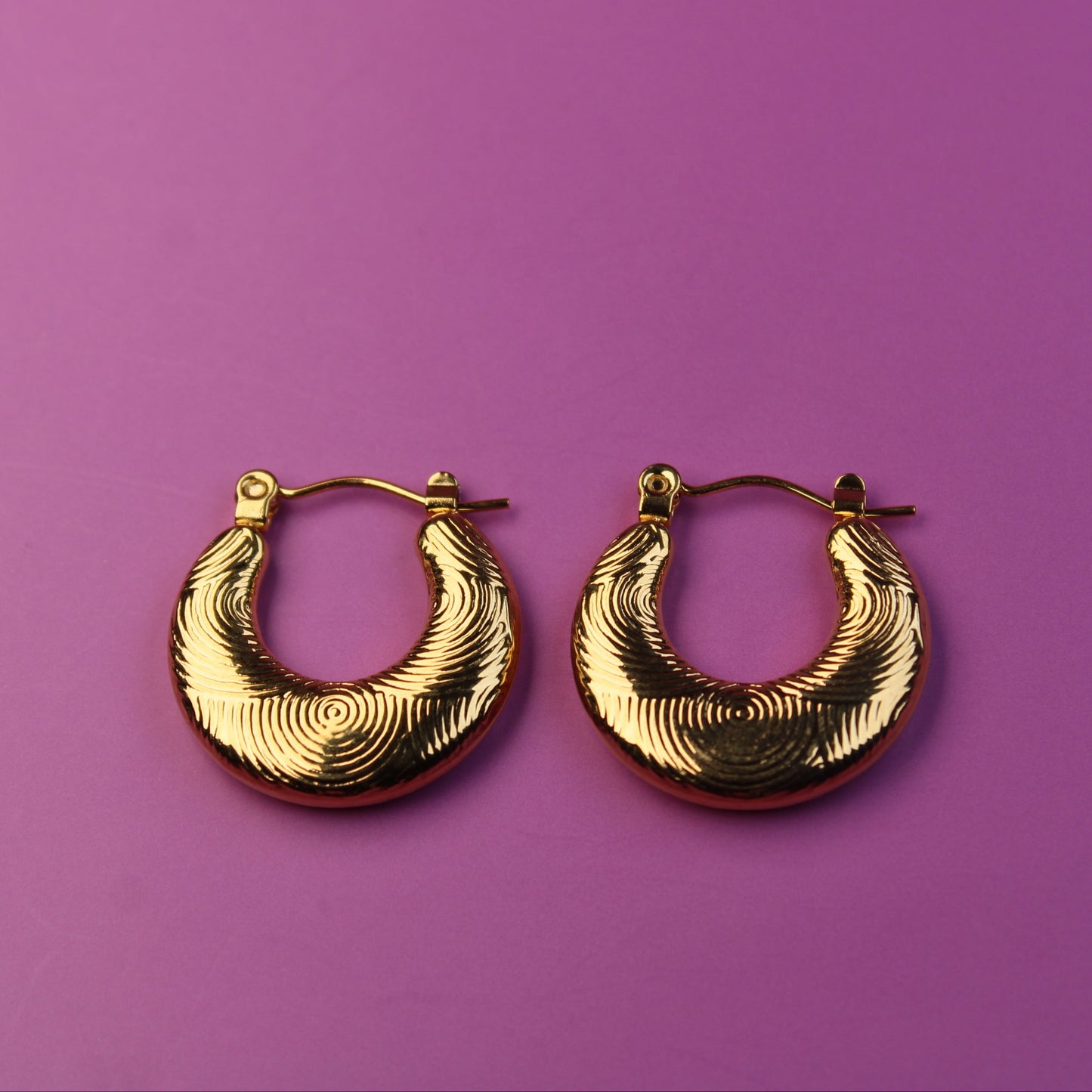 Gold hoop earrings on a purple background