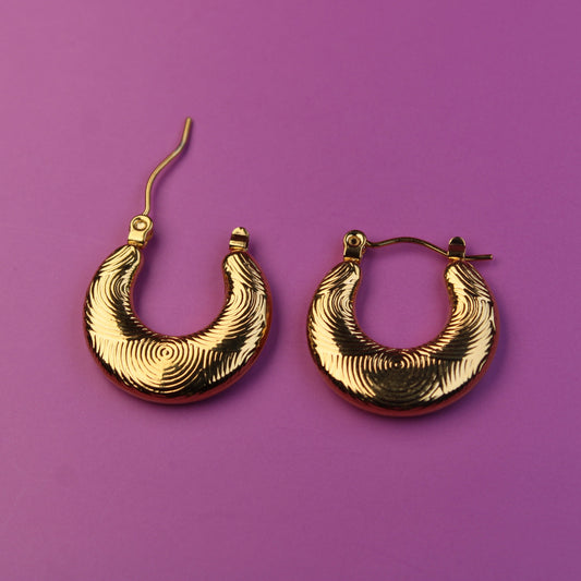 Gold hoop earrings on a purple background