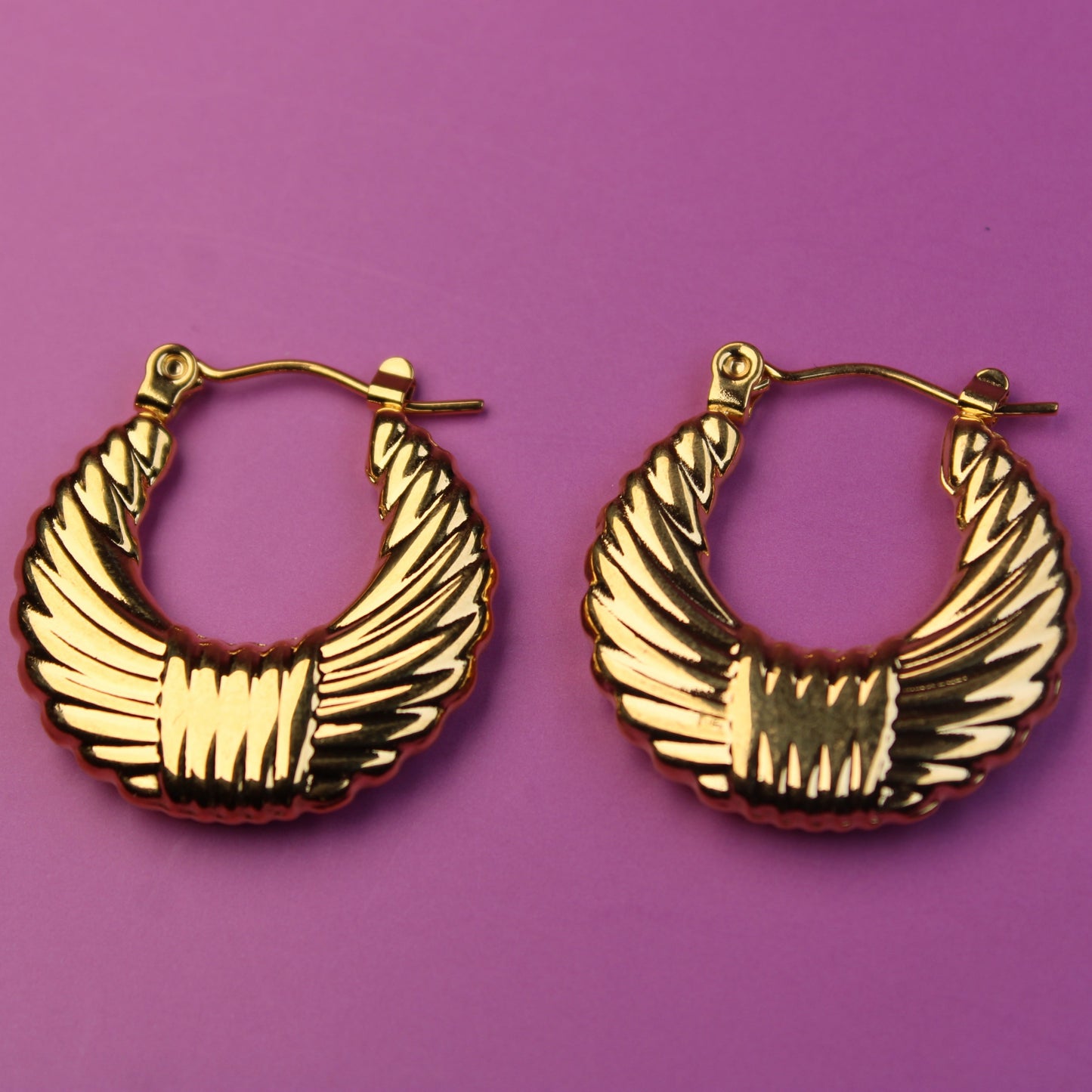 Gold hoop earrings on a purple background
