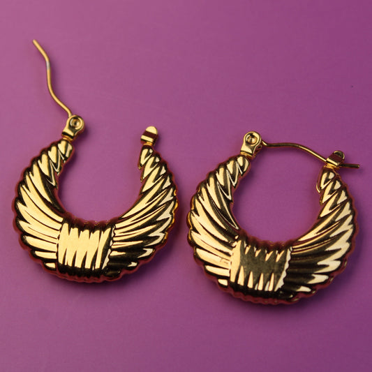 Gold hoop earrings on a purple background