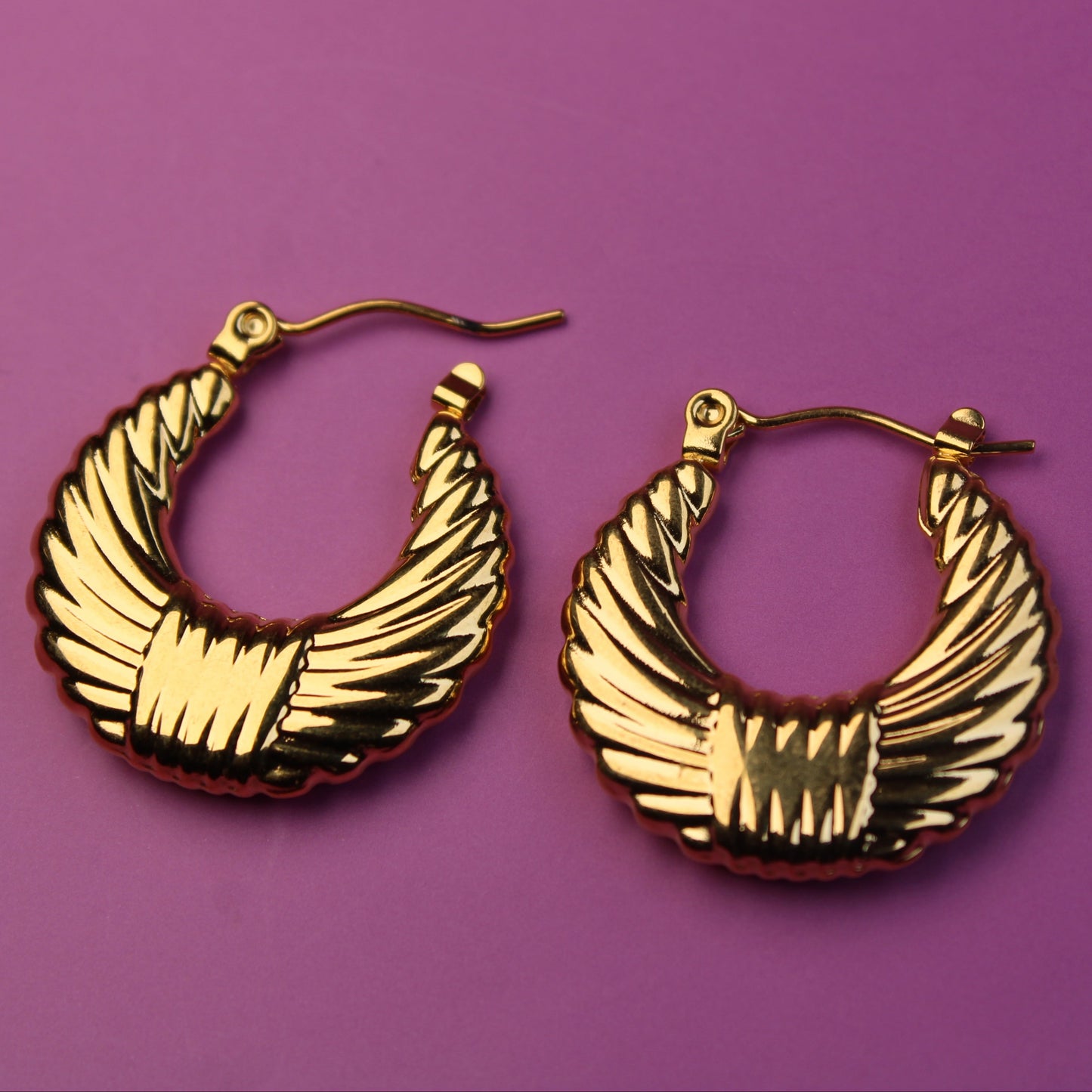 Gold hoop earrings on a purple background