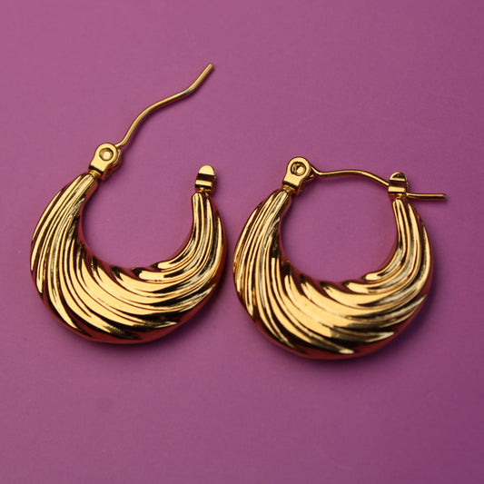 Gold hoop earrings on a purple background