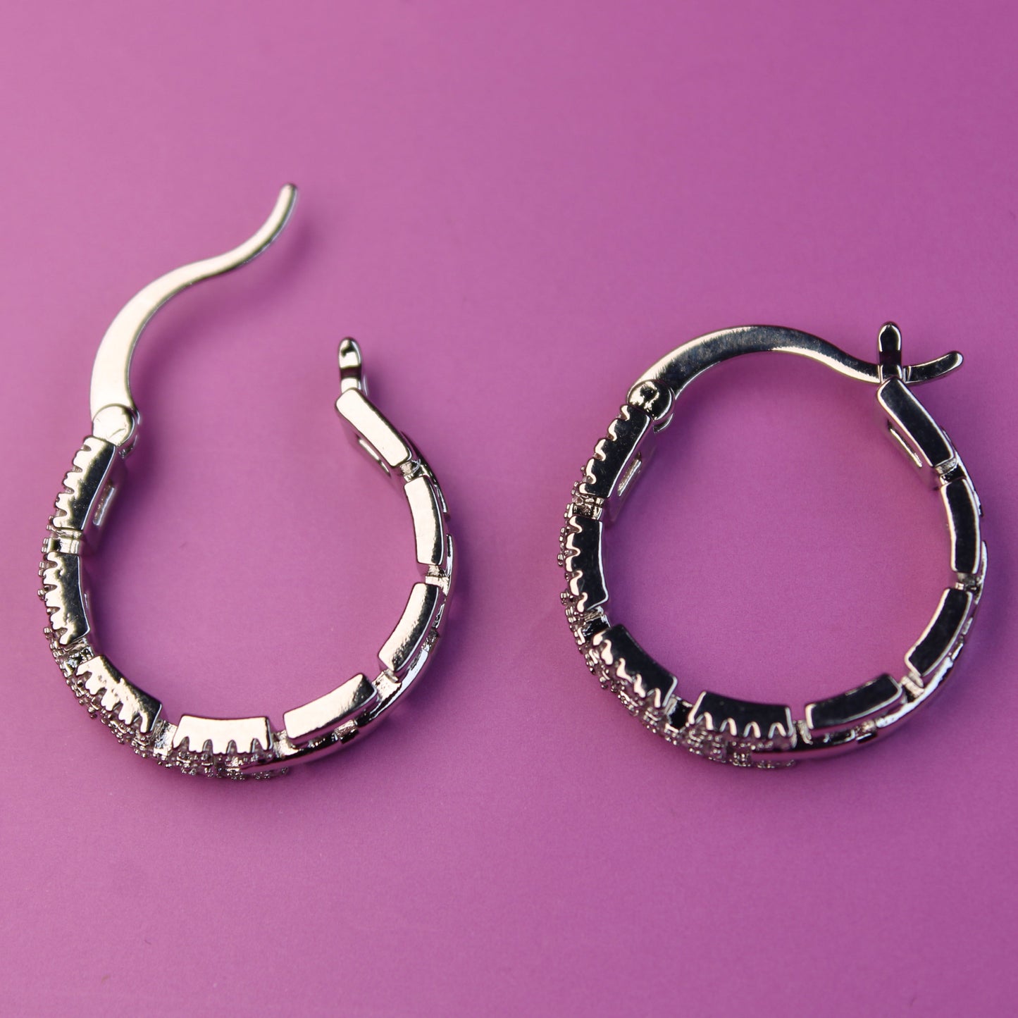 Pair of silver hoop earrings on a purple background