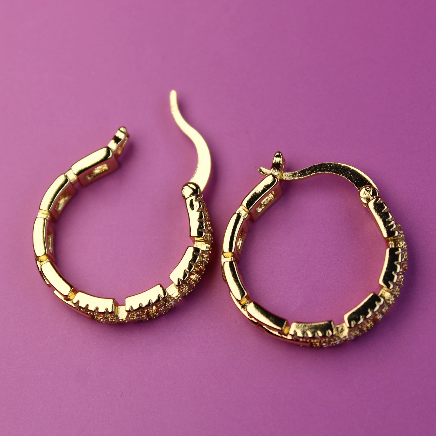 Gold hoop earrings on a purple background