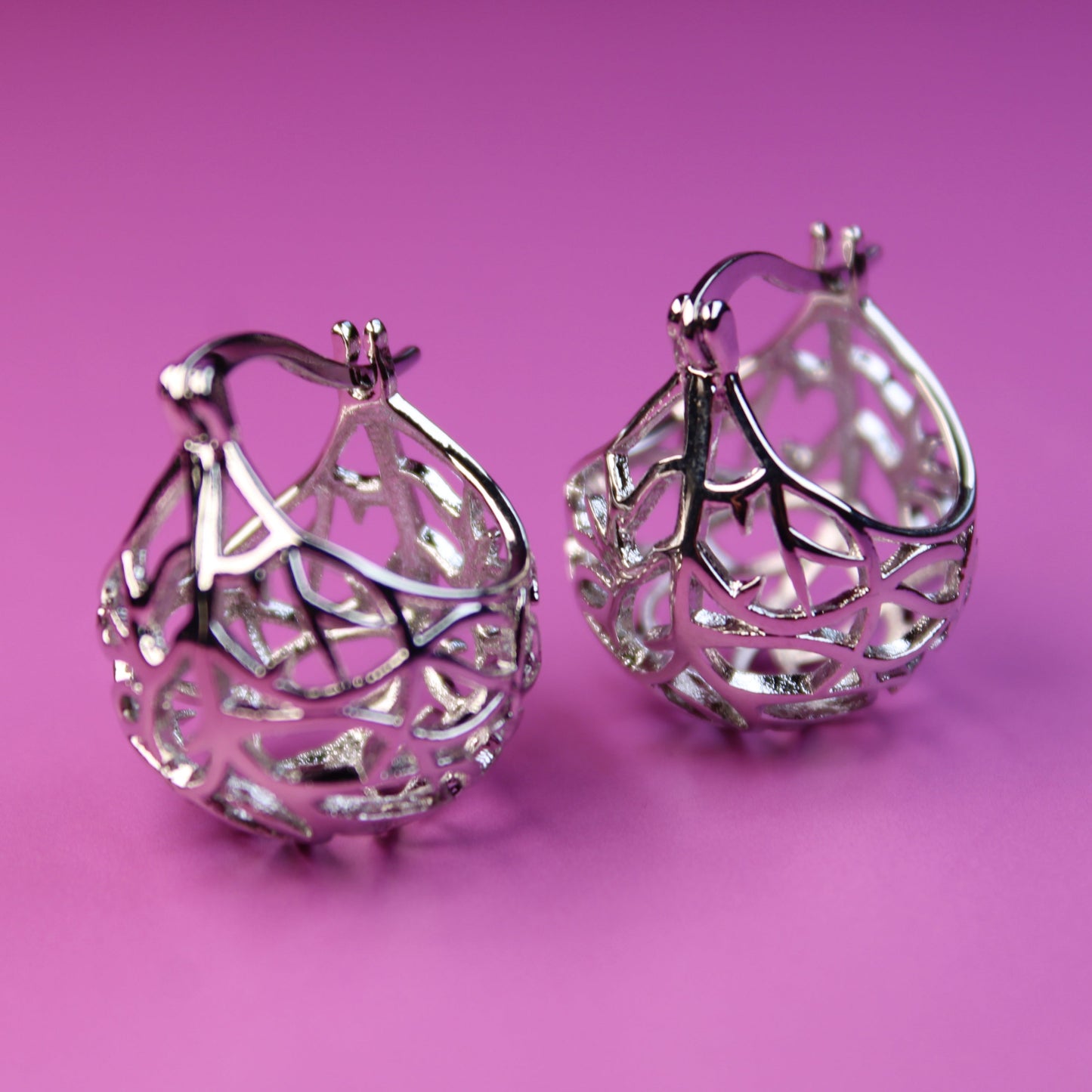 Silver hoop earrings on a pink background