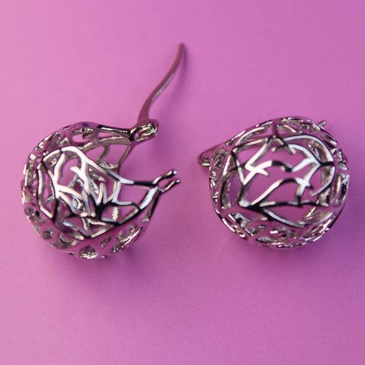 Silver earrings on a pink background