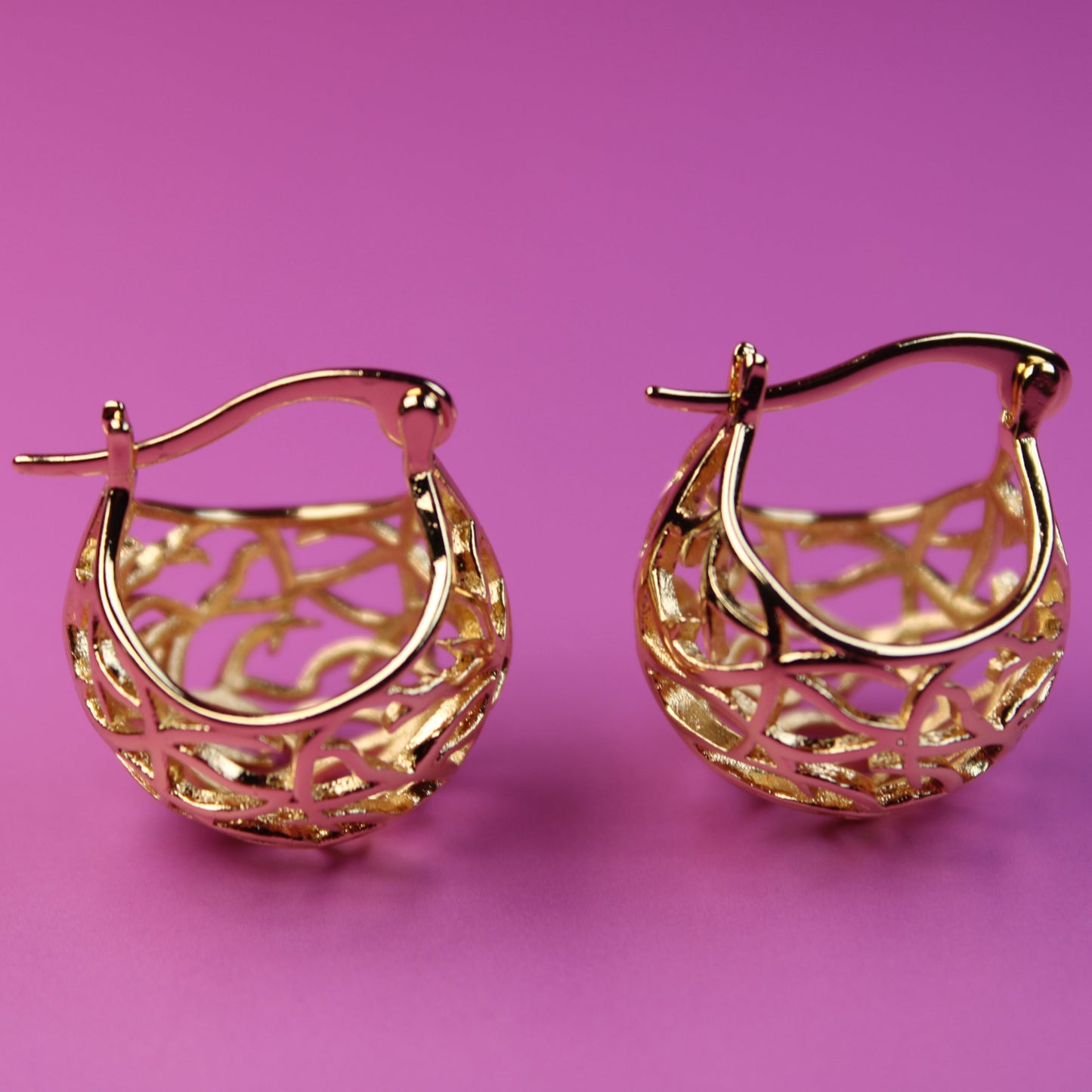 Gold hoop earrings on a pink background