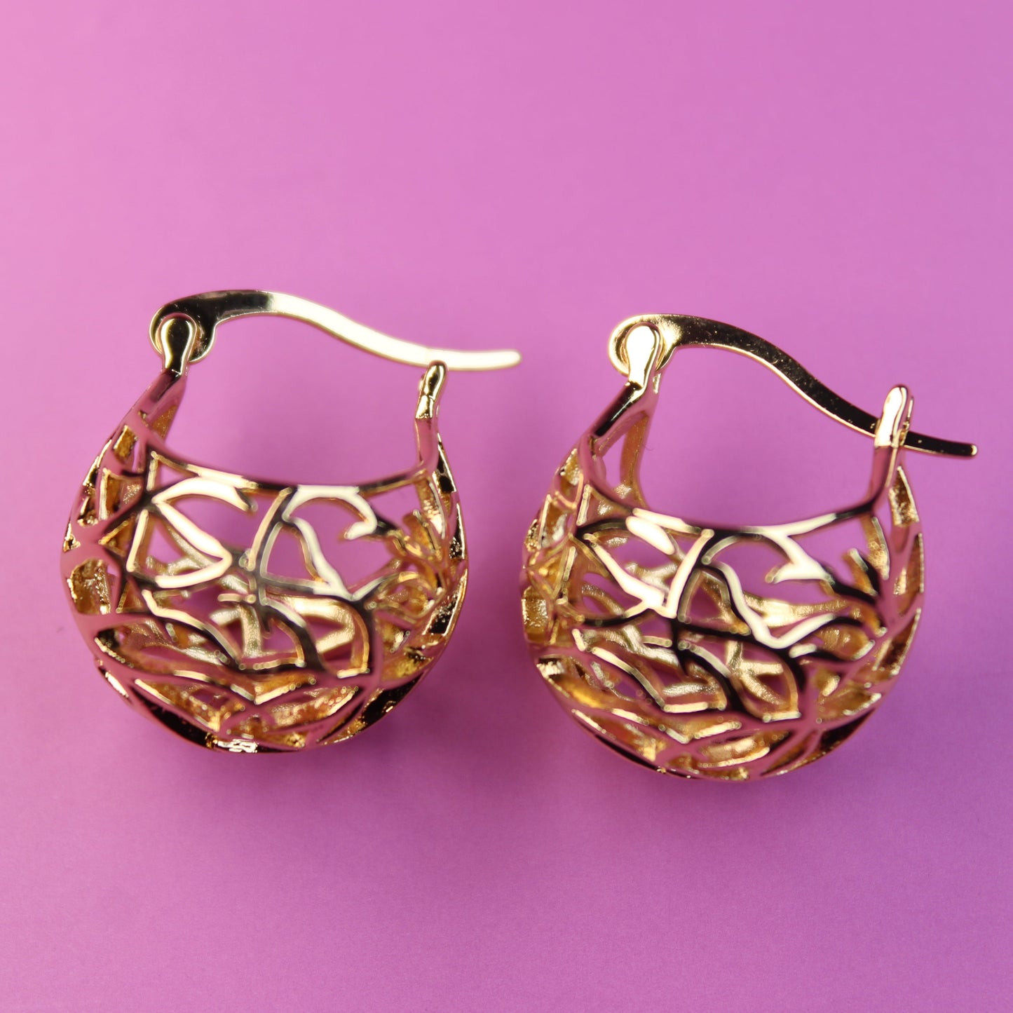 Gold hoop earrings on a pink background