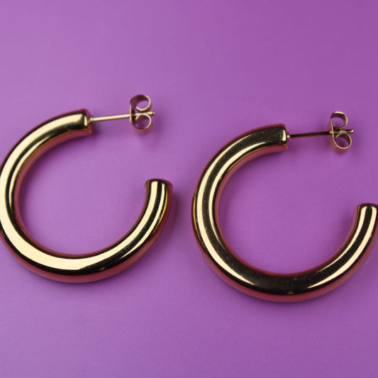 Gold hoop earrings on a purple background