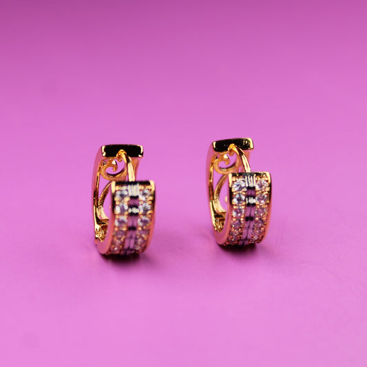 Gold hoop earrings with pink gemstones on a pink background