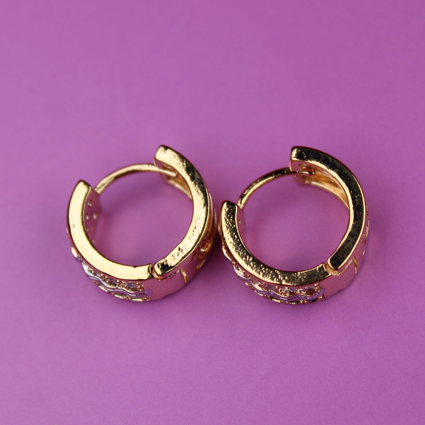 Gold hoop earrings on a purple background