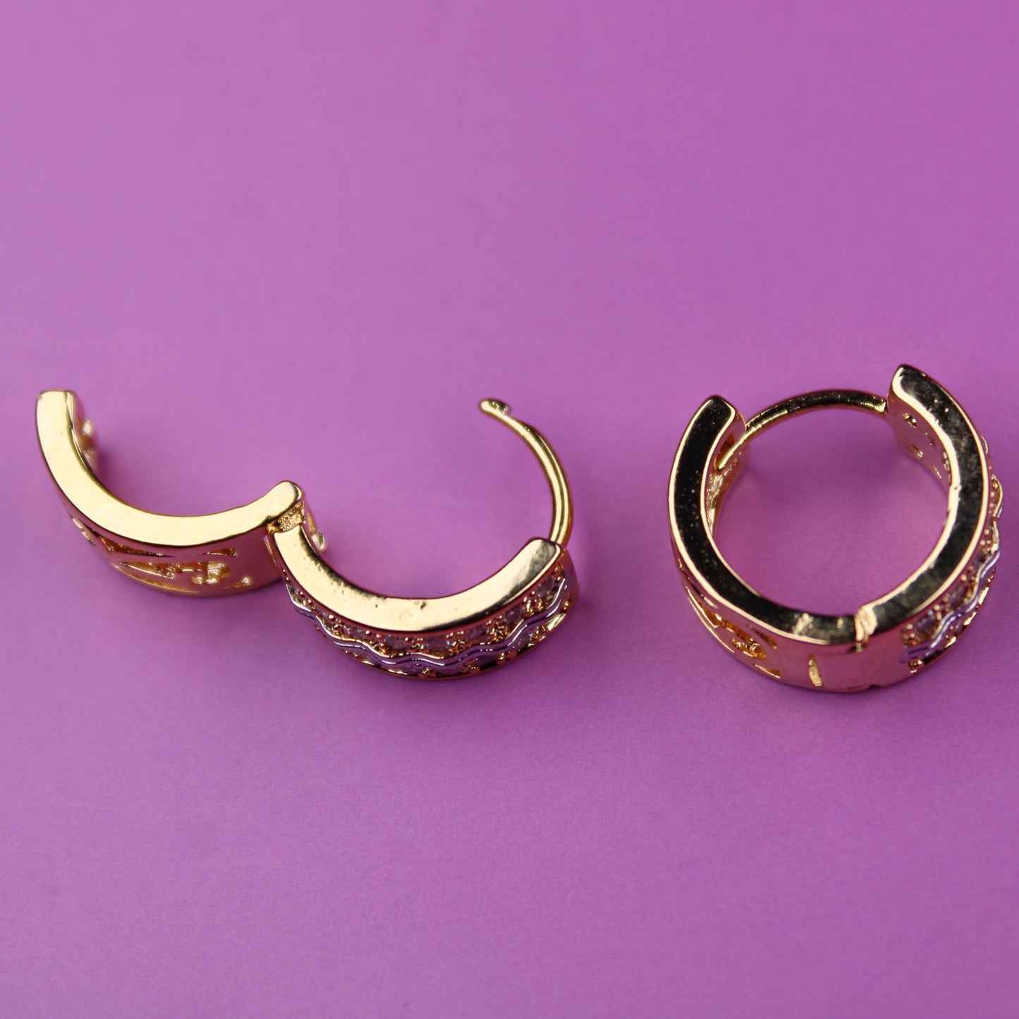 Gold hoop earrings on a purple background