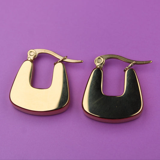 Gold hoop earrings on a purple background
