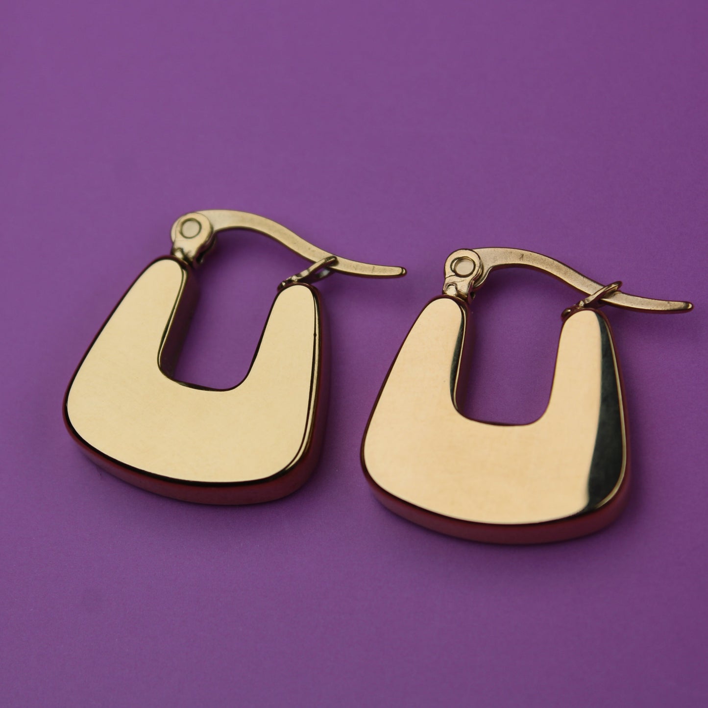 Gold hoop earrings on a purple background
