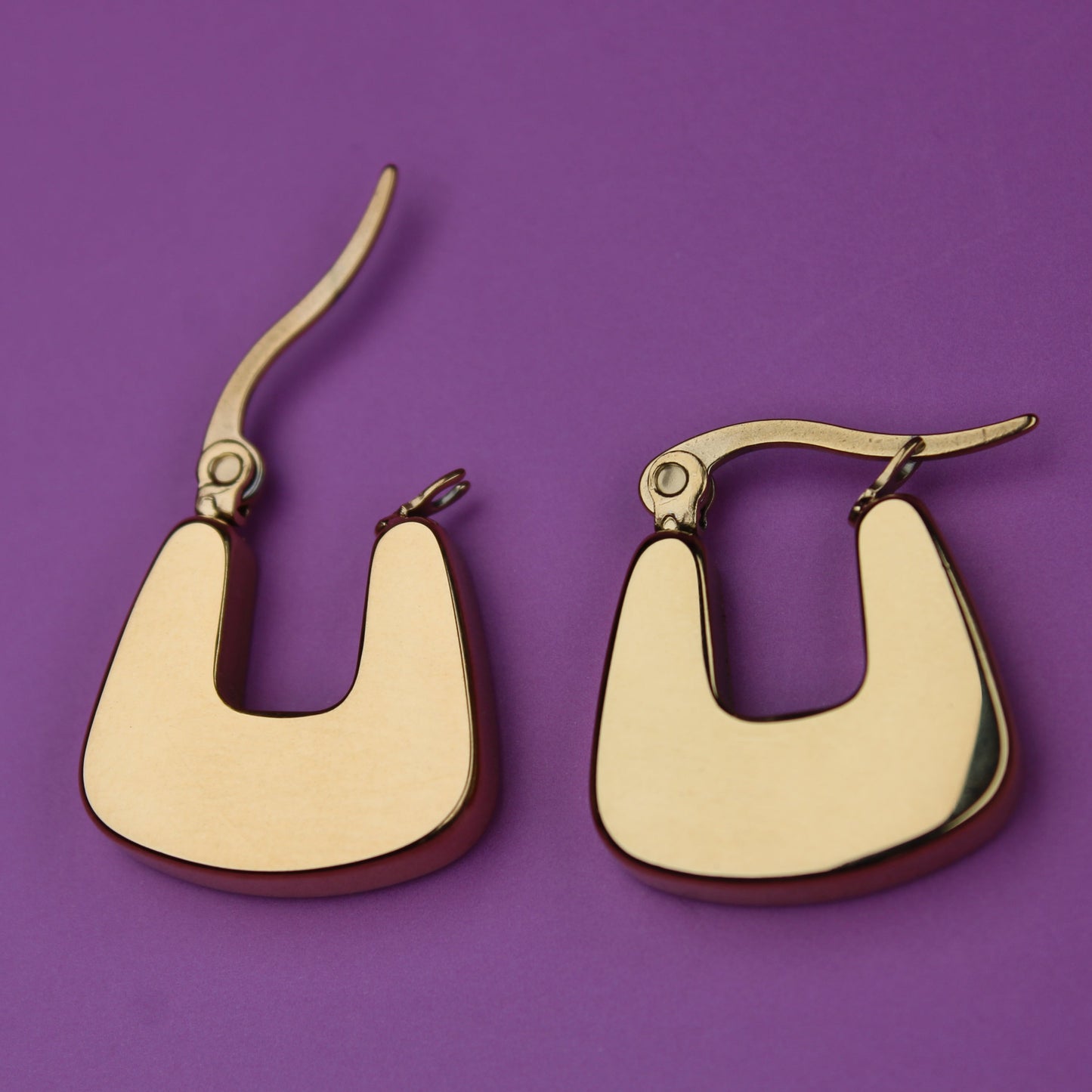 Gold hoop earrings on a purple background