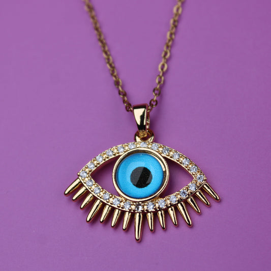 Gold necklace with an eye-shaped pendant on a purple background