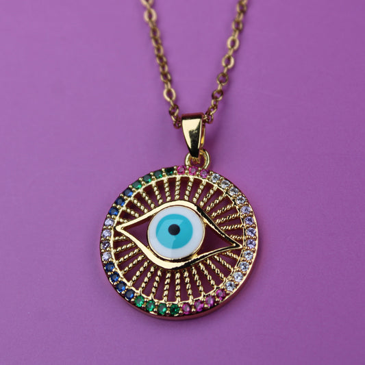 Gold necklace with an eye-shaped pendant on a purple background