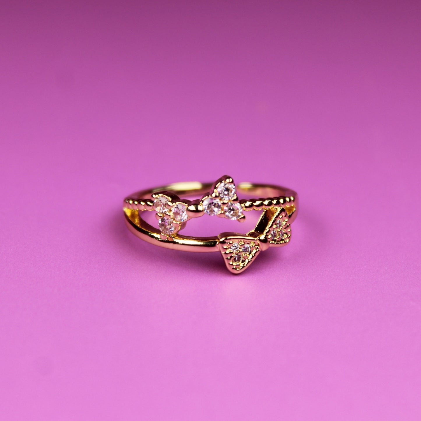 Gold ring with heart designs on a pink background