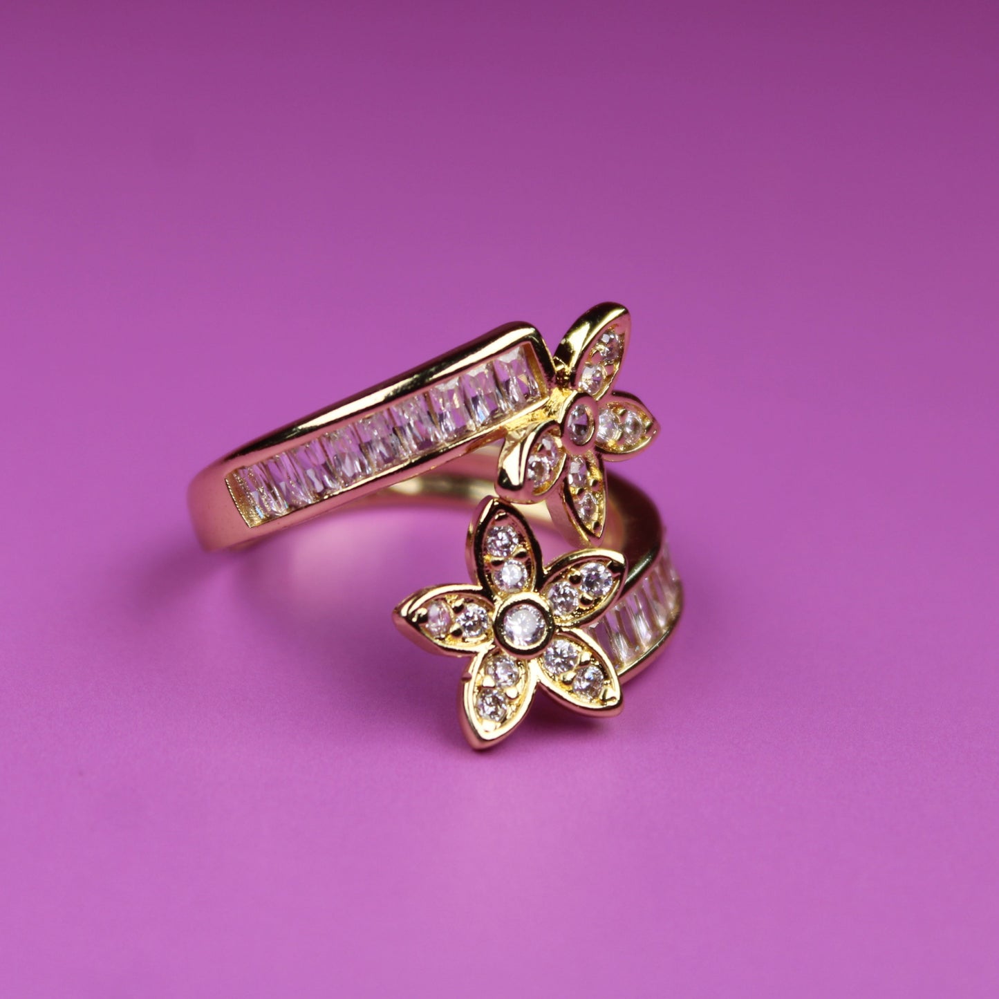 Gold ring with butterfly design on a pink background