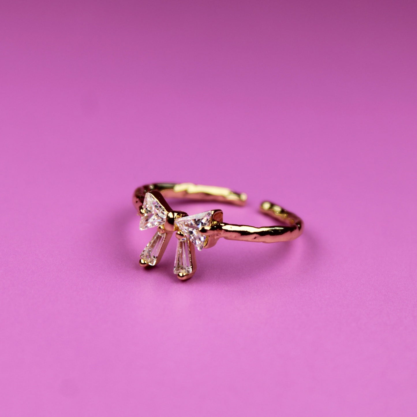 Gold ring with a diamond on a pink background