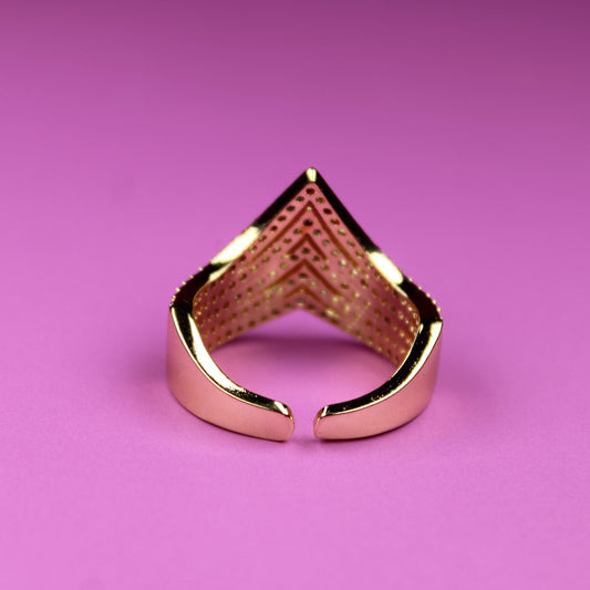 Gold ring with a unique design on a pink background