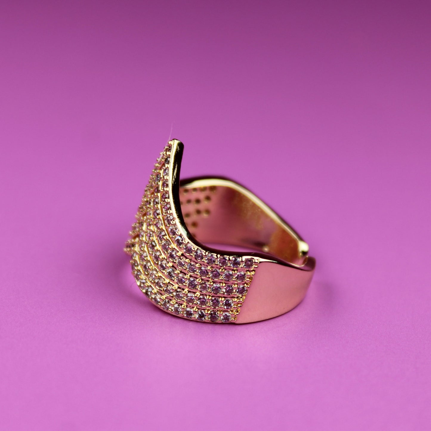 Gold ring with gemstones on a pink background